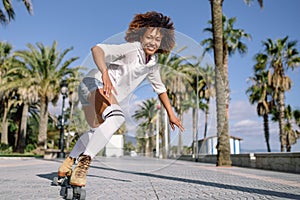 Black woman on roller skates rollerblading in beach promenade wi