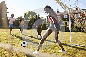 Black woman saving goal during a game of football in garden