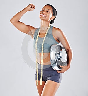 Black woman, scale and slim body in happy achievement, victory or win for healthy diet against a grey studio background