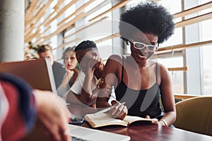 Black woman sitting in front of group of multi ethnic people with alternative girl with green hair is working together