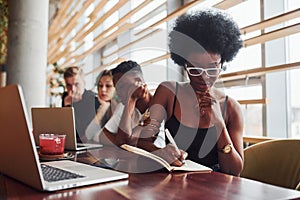 Black woman sitting in front of group of multi ethnic people with alternative girl with green hair is working together