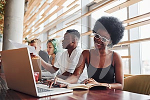 Black woman sitting in front of group of multi ethnic people with alternative girl with green hair is working together