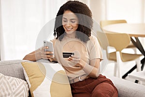 Black woman, smartphone and credit card on sofa for ecommerce, online banking and paying bills in living room. African