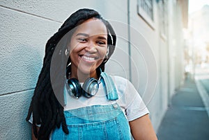 Black woman, smile and happy urban student girl on city street smiling and leaning against a wall outside on commute to