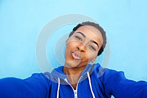 Black woman smiling against blue wall with hands behind head