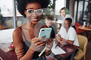 Black woman standing in front of group of multi ethnic people with alternative girl with green hair is working together