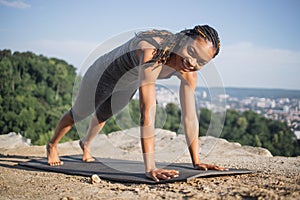 Black woman standing in plank position on yoga mat