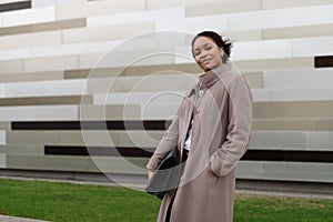 A black woman stands in front of an office building with a leather folder.