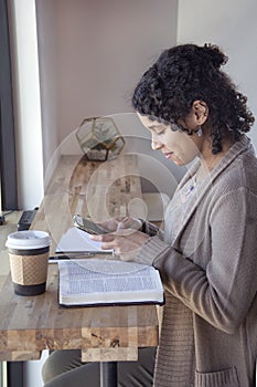 Black woman studies her bible and uses phone