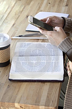 Black woman studies her bible and uses phone