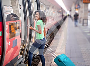Black woman taking the train in station platform holding phone