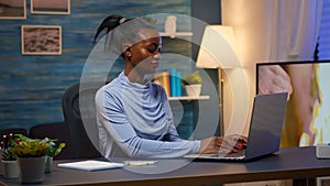 Black woman typing on computer and writing on stick notes