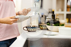 Black woman using tablet computer while cooking in kitchen