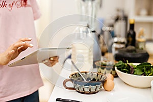 Black woman using tablet computer while cooking in kitchen