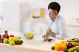 Black Woman Using Tablet Cooking Browsing Recipes Online In Kitchen