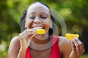 Black woman, vitamin C and eating orange slice for natural nutrition or citrus diet in nature outdoors. Happy African