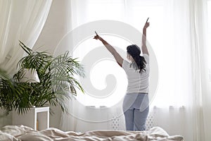 Black woman waking up in morning and standing near window at home