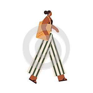 Black woman walking with tote bag. Modern female in casual clothes, pants, top and flip-flops, going. African-American