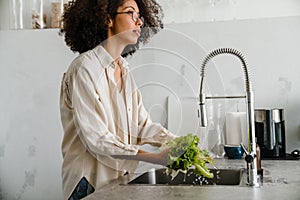 Black woman washing lettuce while cooking at home