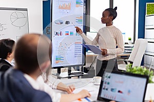 Black woman worker explaning company statistics in front of colleagues