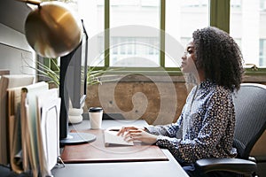 Black woman working at a computer in an office, side view photo