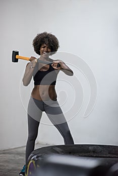 Black woman workout with hammer and tractor tire