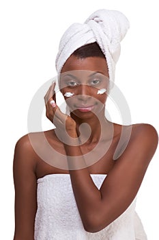 Black woman wrapped in towel moisturizing face