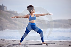 Black woman, yoga and fitness for wellness at beach with peaceful mind, warrior pose and body. African person, zen and