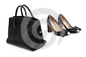 Black women\'s leather bag and a pair of black high-heeled shoes on a white background