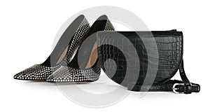 Black women`s saddle bag and high heeled shoes on white background