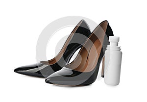 Black women`s shoes and bottle with care product on white background