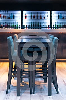 Black wooden bar table with chairs in the pub with bottles at the background