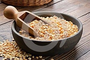 Black wooden bowl of dried peas, wooden scoop full of dry peas