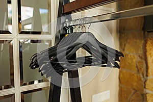 Black wooden clothes hangers without clothes on metal rack at the entrance to the restaurant. Hallway of a hotel or