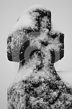 Black wooden cross covered in snow