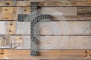 Black wooden cross with the Lord`s prayer on the shabby natural
