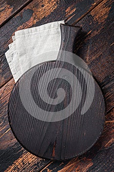 Black wooden Cutting board over towel on kitchen table. Wooden background. Top view. Copy space