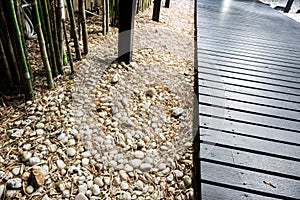 Black wooden garden path on white pebbles with bamboo.