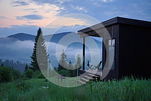 Black wooden house with foggy mountain view evening after sunset