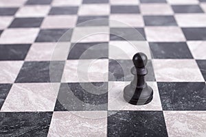 Black wooden pawn on chessboard