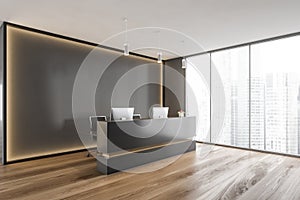 Black and wooden reception room desk with computers near window