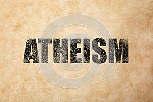 Black word Atheism on beige textured background. Philosophical or religious position
