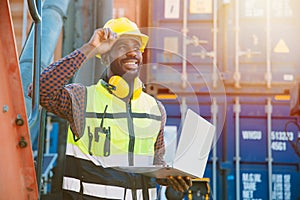 Black worker African working engineer foreman in port cargo shipping with computer laptop