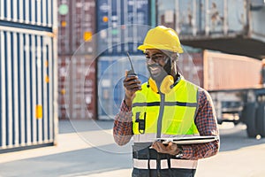 Black worker African working engineer foreman radio control in port cargo shipping customs container yard