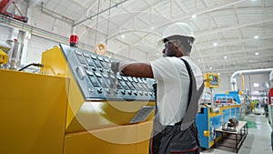 Black worker entering data in CNC machine at pvc window factory to get the production going