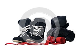 Black wrestling shoes, black boxing gloves and unwound red protective bandages for martial arts isolated on a white background