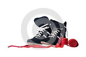 Black wrestling shoes and unwound red protective bandages for martial arts isolated on a white background