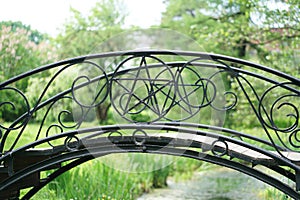 Black wrought iron bridge with goth pentagram star inside. summer day photo. nobody.