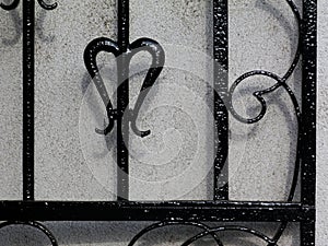 Black wrought iron gate closeup detail. white stucco wall