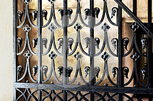 Black wrought iron gate closeup detail. white stucco wall